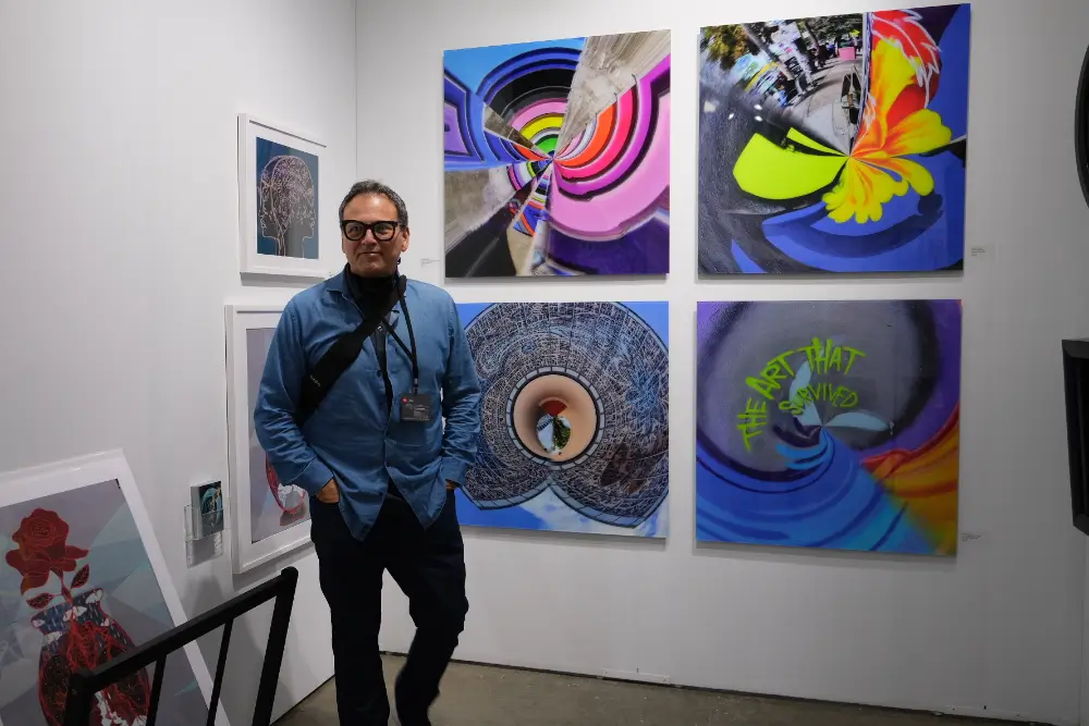 A man standing in front of four paintings.