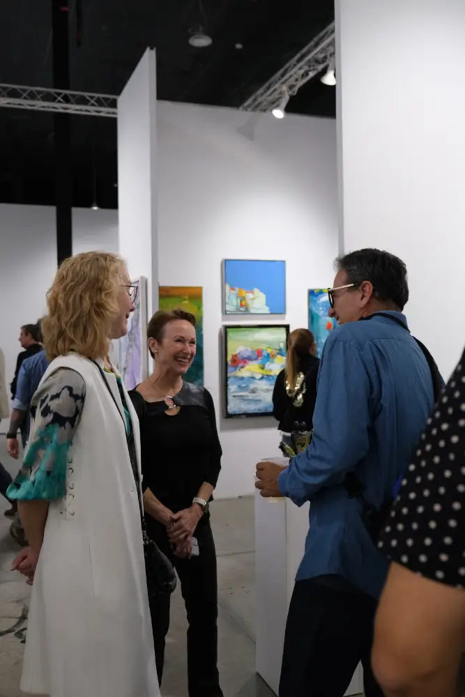 A group of people standing around in an art gallery.