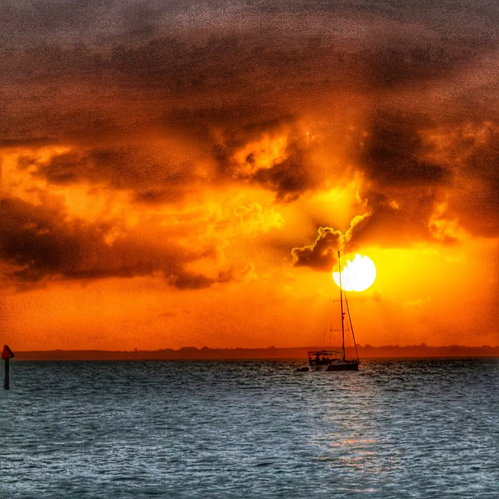 A boat is in the water at sunset.