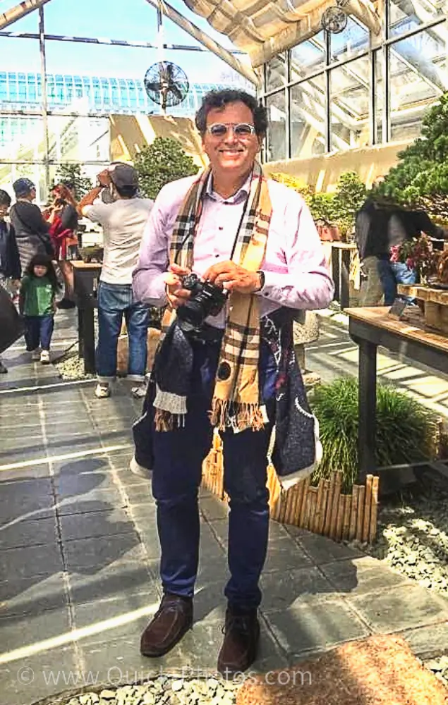 A woman standing on the sidewalk with her camera.