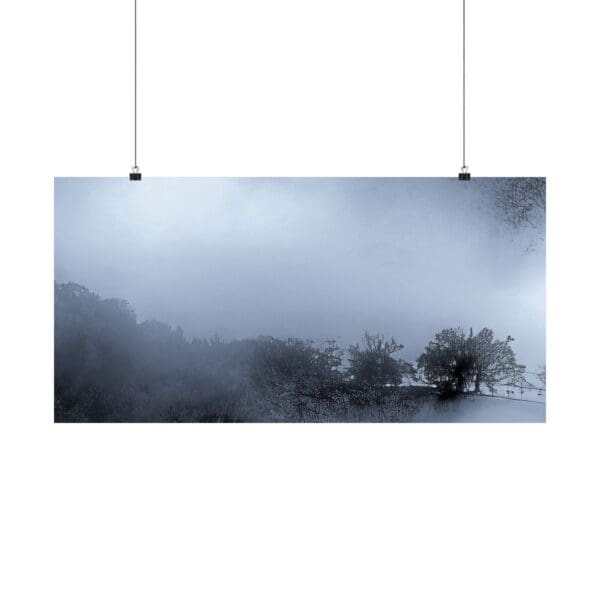 A hanging poster of trees and mountains in the fog.